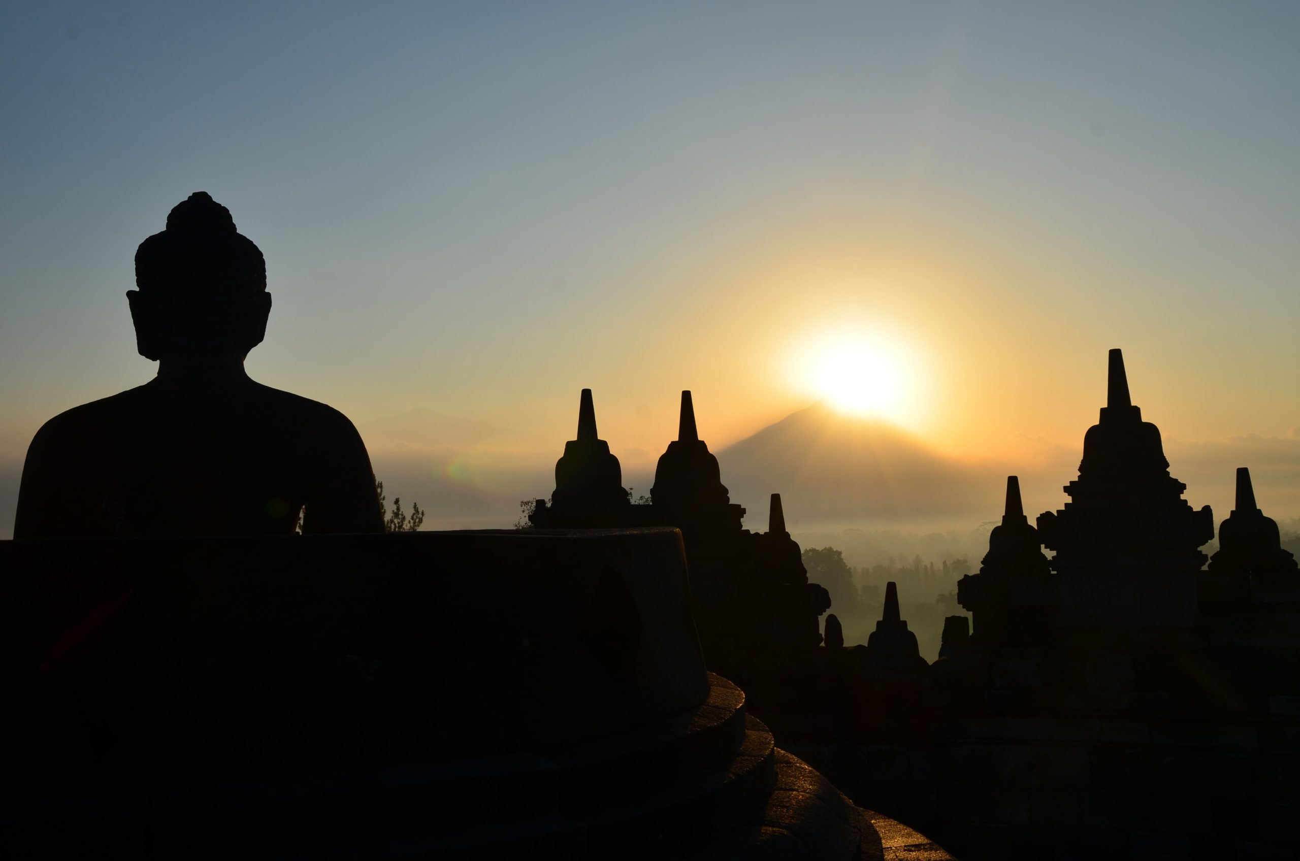 Borobudur al amanecer — Java, Indonesia Silueta de Buda y estupas de Borobudur al amanecer con volcán al fondo, Java, Indonesia