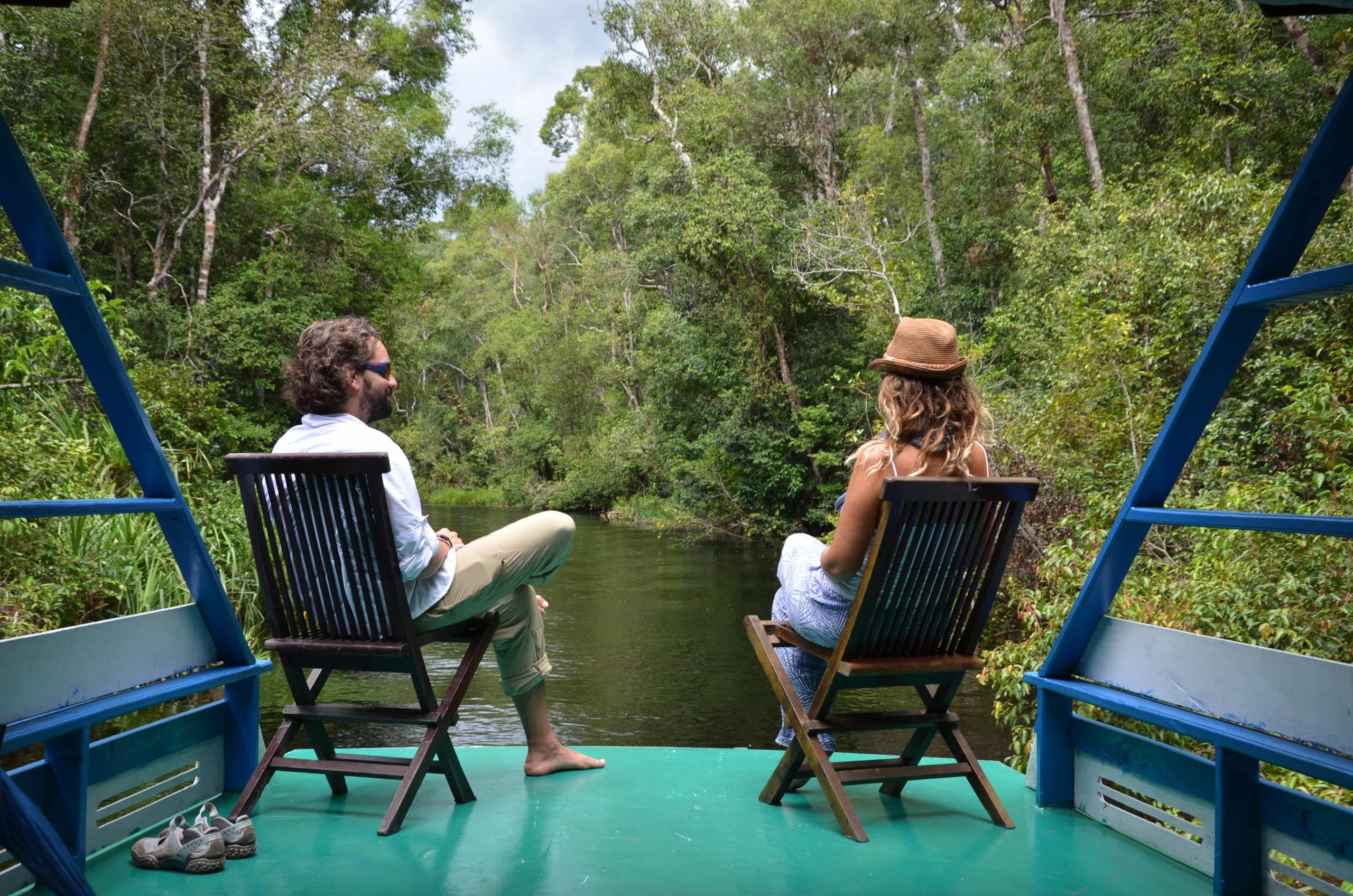 Pareja en klotok por el río Sekonyer — Borneo, Indonesia Pareja navegando en klotok por el río Sekonyer entre selva primaria, Parque Nacional Tanjung Puting, Borneo, Indonesia