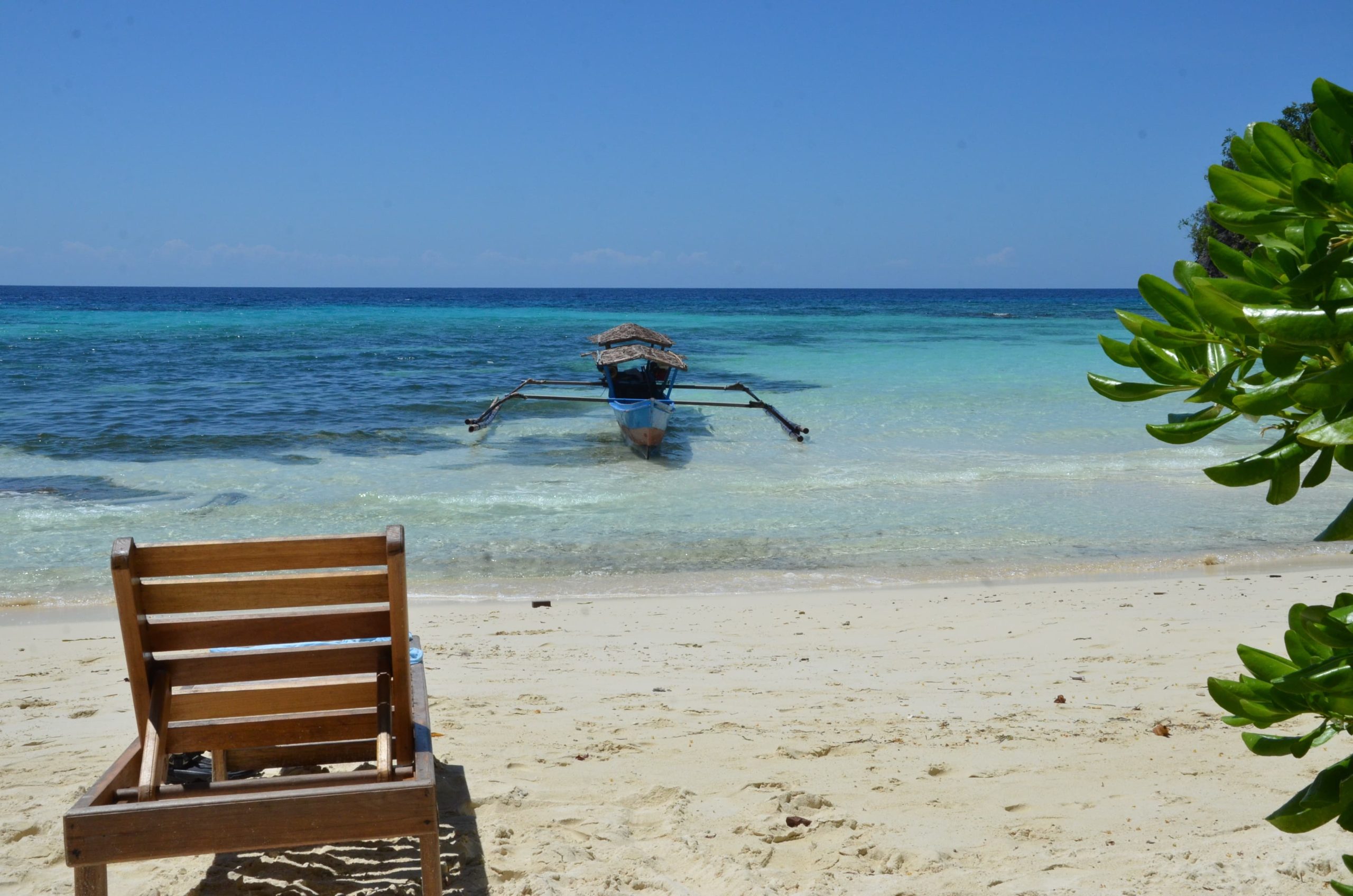 Playa secreta en las islas Togian — Sulawesi, Indonesia Playa desierta con barca tradicional y aguas turquesas en las islas Togian, Sulawesi, Indonesia