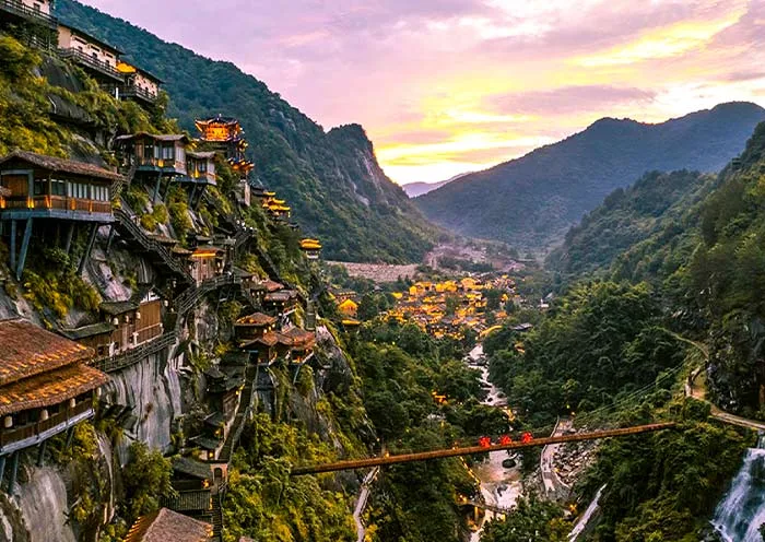 Casas colgadas de los acantilados del valle de Wangxian iluminadas al anochecer, Shangrao, China