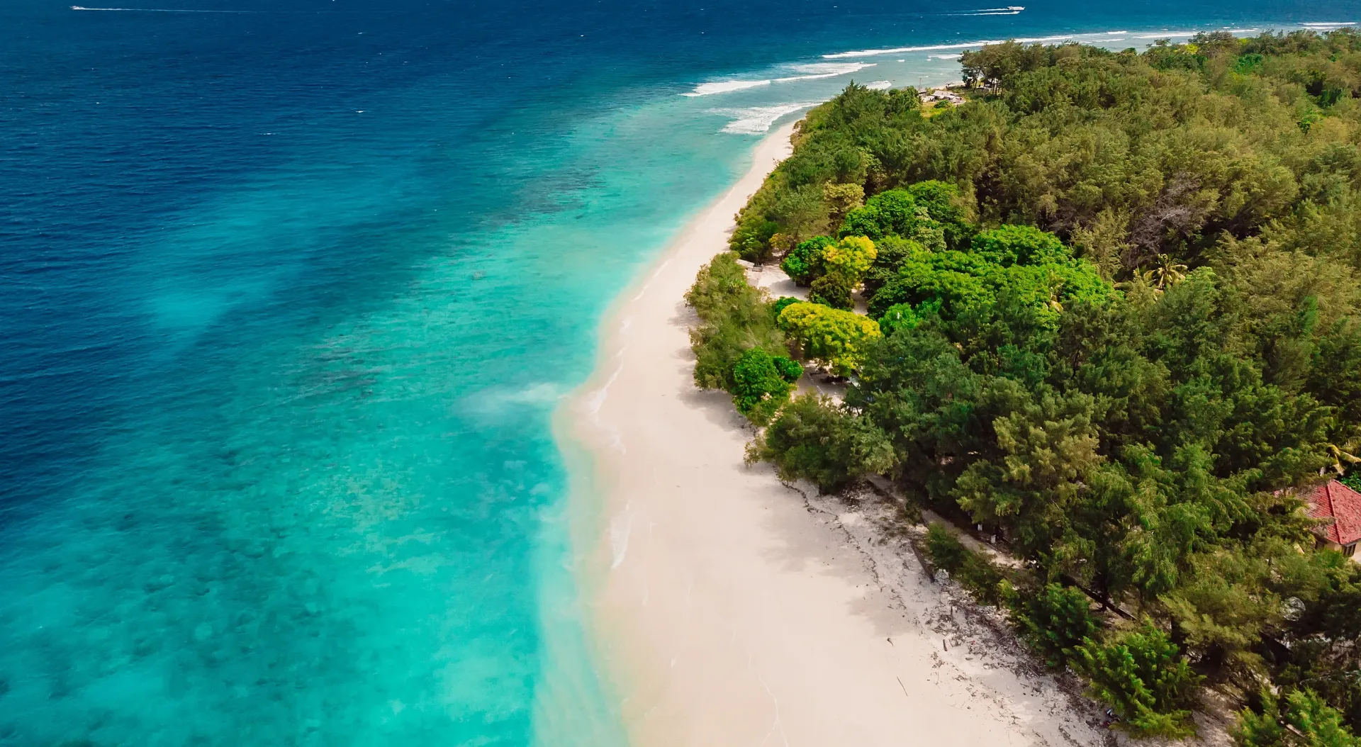 Vista aérea de una playa de arena blanca y aguas turquesa con arrecife en las islas Gili, Indonesia